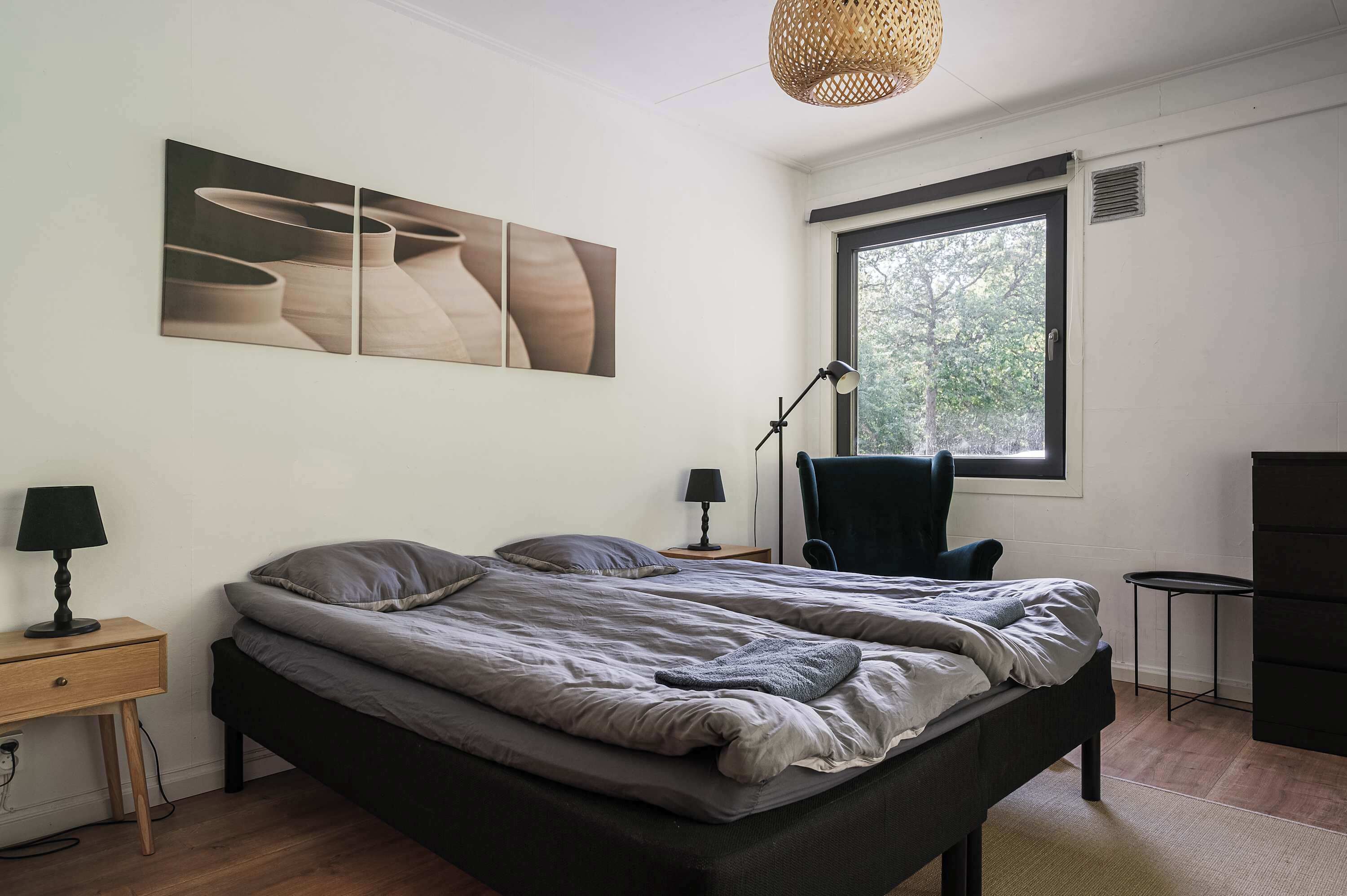 A bedroom with a bed, a desk, a chair, a lamp, and a window.