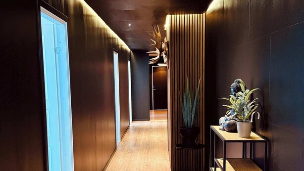 A modern hallway with wooden flooring, dark walls, and a small table with plants. - Ladhus One - Fancy Nature Hill home by the lake (Floda)