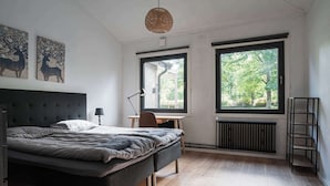 A bedroom with a bed, a desk, a chair, a radiator, and two windows. - Ladhus One - Fancy Nature Hill home by the lake (Floda)