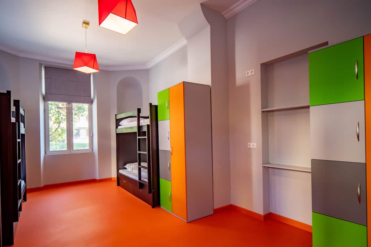 A room with bunk beds, a wardrobe, and a window.