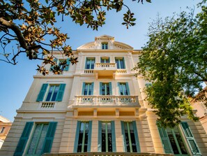 A multi-story building with a classical architectural style, featuring a central balcony with balustrades, multiple windows with shutters, and a symmetrical facade. - Banana's Camp - Hostel (Cannes)