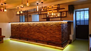 A reception desk with a wooden brick wall, hanging pendant lights, and framed motivational quotes. - Banana's Camp - Hostel (Cannes)