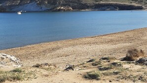 A coastal landscape with a clear blue lake, sandy beach, and a hill in the background. - House in a typical hamlet - Cabo de Gata Park (Carboneras)