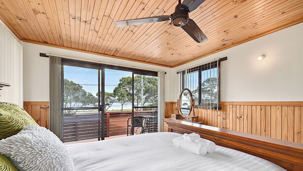 A bedroom with a large bed, wooden ceiling, and a view of the outdoors. - Hook, Wine & Sinker Retreat (Stieglitz)