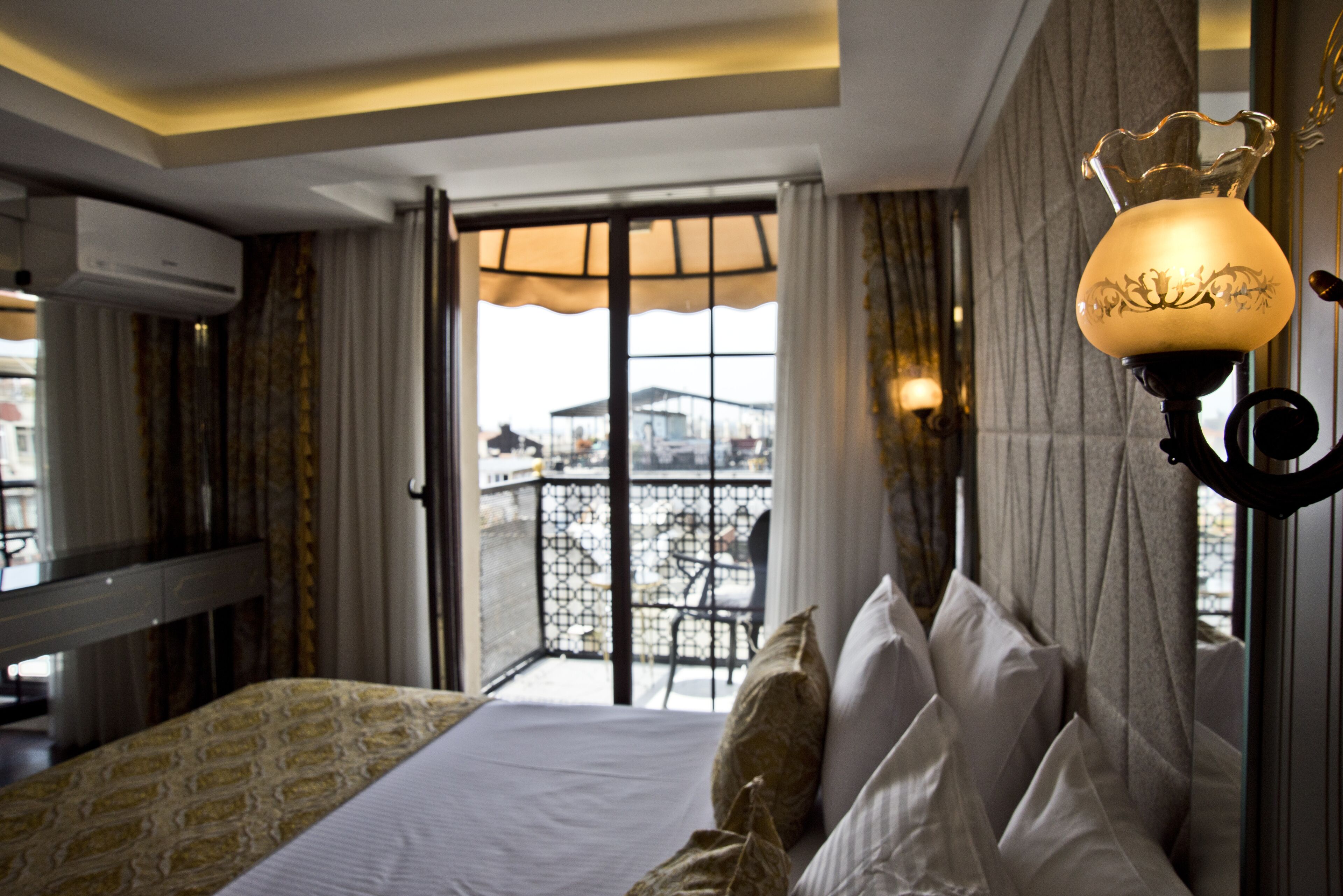 Une chambre d’hôtel avec un lit, un balcon offrant une vue agréable et une applique murale décorative.