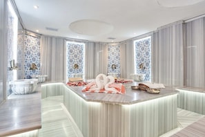Un baño lujoso con tocador de mármol, ventanas amplias y una decoración central con forma de cisne.