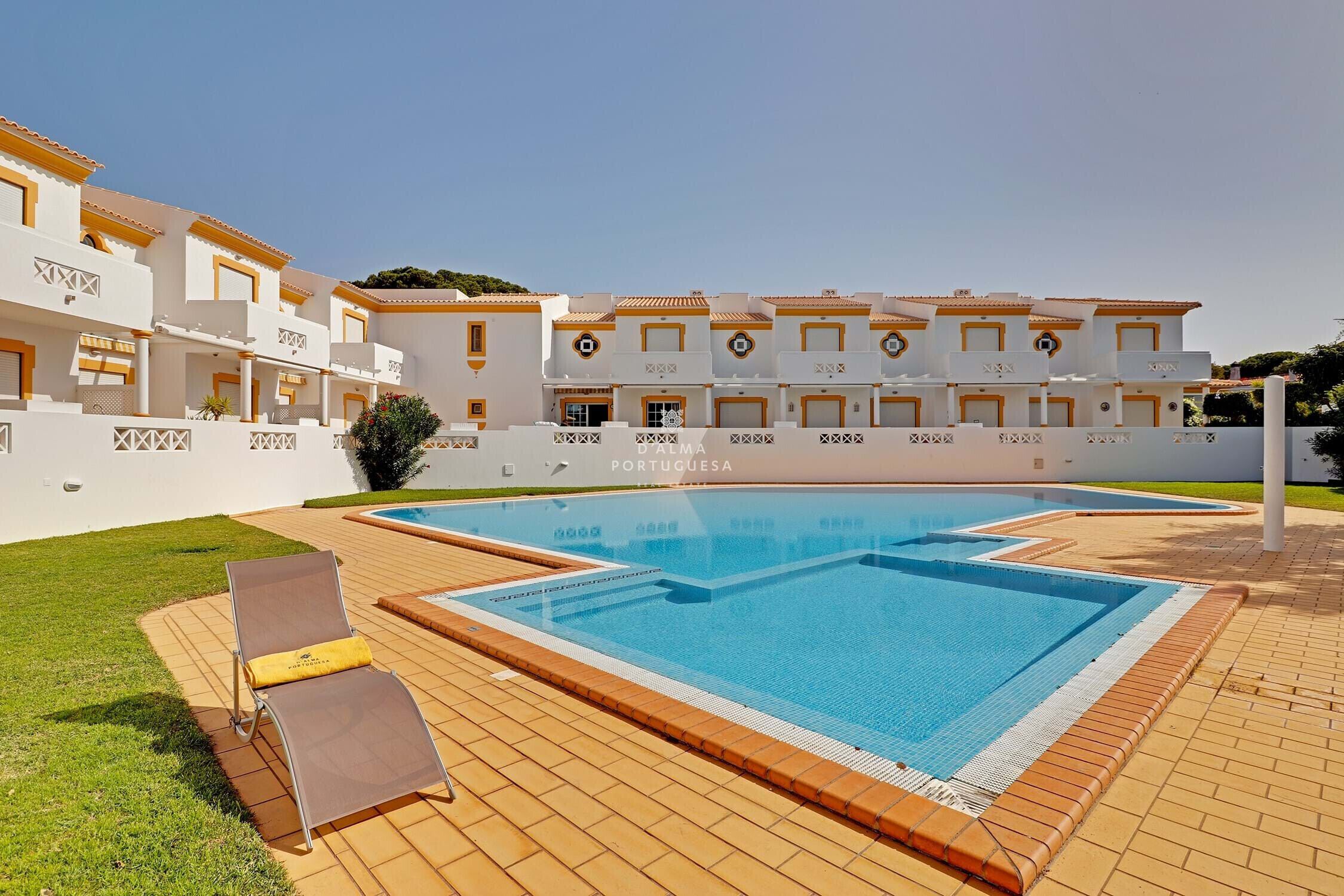 A swimming pool with a sun lounger and a tiled deck area.