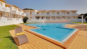 Une piscine avec des chaises longues et une terrasse carrelée.