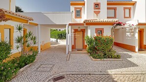 Une cour dallée de pierres, une entrée centrale avec une porte en bois et une enseigne indiquant « ALMA PORTUGUESA ».