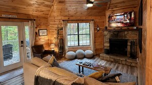 Ein gemütliches Blockhaus-Interieur mit einer Couch, Kamin und Deckenventilator.