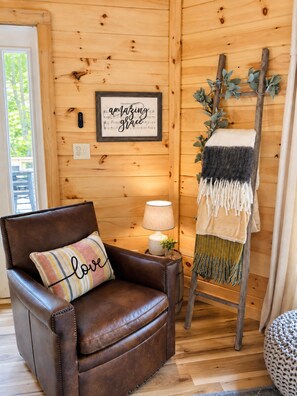 A cozy room with a brown leather chair, a framed inspirational quote, a lamp, and a ladder with a blanket. - Cozy Gatlinburg cabin tucked in the woods with a private hot tub, wood-burning fireplace, shared seasonal pool, and room for up to 5 guests—all just minutes from downtown, restaurants, and top Smoky Mountain attractions. (Gatlinburg)