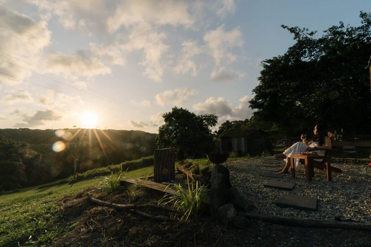 A rustic outdoor setting with a wooden table and chairs, surrounded by gravel and greenery.
