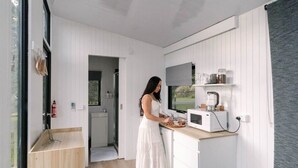 A compact kitchen with white cabinetry, a wooden countertop, and a microwave. - Rainforest Sunsets by Tiny Away (Kuranda)