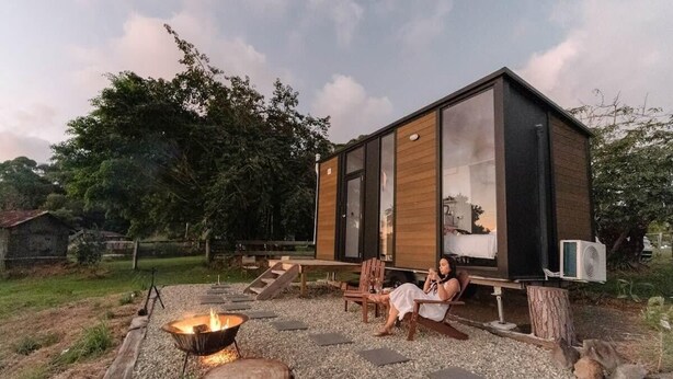 A modern cabin with a large glass window, a fire pit, and a wooden deck. - Rainforest Sunsets by Tiny Away (Kuranda)