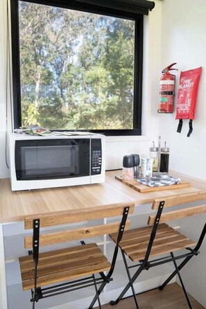 Een keuken met een magnetron, houten tafel en stoelen.