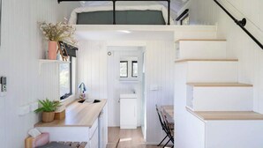 Un interior moderno y compacto con un entrepiso para dormir, kitchenette y comedor.