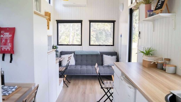 Un espacio habitable compacto con sofá, mesa de comedor y zona de cocina.