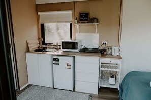A compact kitchenette with a microwave, small refrigerator, and a coffee maker.
