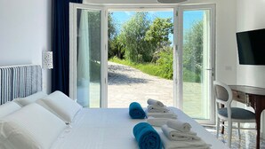 Une chambre d’hôtel équipée d’un lit, d’un bureau, d’une chaise et offrant une vue sur un jardin grâce à une porte vitrée.