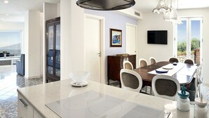 Une cuisine moderne dotée d’un îlot central, d’un coin repas avec une grande table et d’une vue sur l’extérieur.