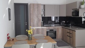 A modern kitchen with wooden cabinets, a built-in oven, and a microwave. - Studio - Sleeps 2 - Balcony - 5 Min Walk To Beach (St. Paul's Bay)