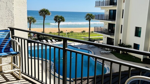 Un balcón con vista a una piscina y una playa.
