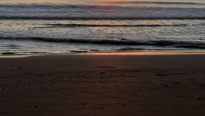 Una playa con un atardecer sobre el océano.