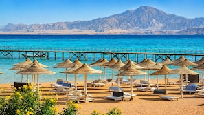 Aan een privéstrand, ligstoelen, parasols, strandlakens