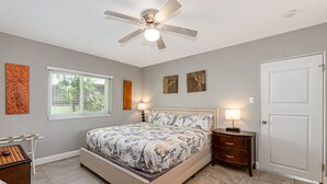 Ein Schlafzimmer mit Bett, Nachttischen, Deckenventilator und einer Tür.