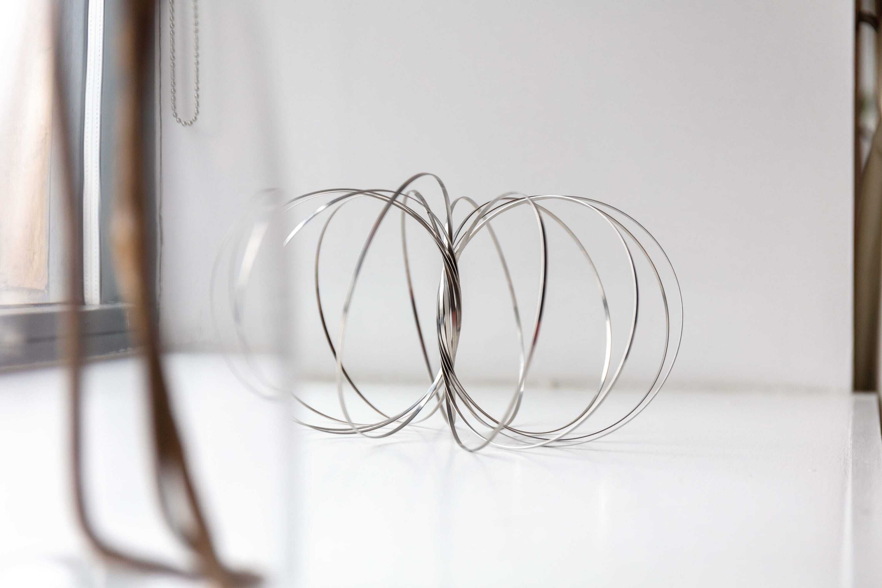 A clear glass object with a metallic wire structure, possibly a decorative item, on a white surface.