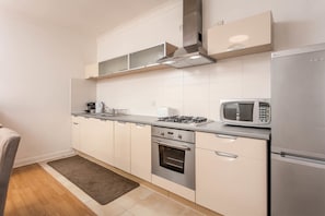 A modern kitchen with white cabinets, stainless steel appliances, and a microwave.