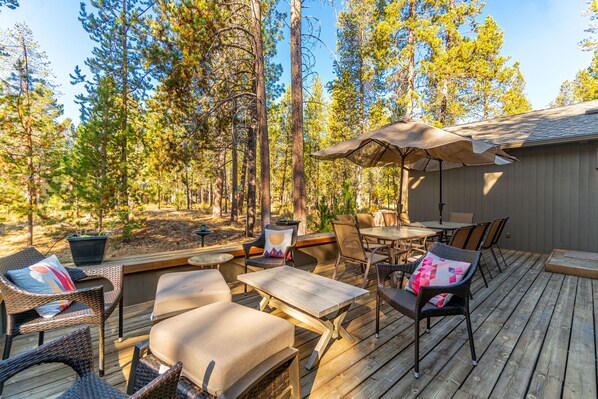 An outdoor deck with wicker furniture, a table, and an umbrella. - Sali10 - Perfect for Families, Great Location, AC, Fireplace, Hot Tub, Ping Pong (Sunriver)