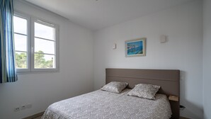 Um quarto com uma cama, uma janela e um quadro na parede.