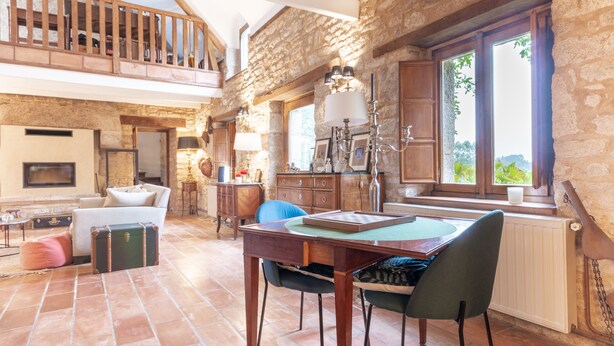 A spacious living area with a high ceiling, stone walls, a wooden balcony, and a dining table with chairs. - Kerguestenen - Longère pour 12 avec piscine (Inguiniel)