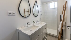 Ein modernes Badezimmer mit zwei Waschbecken, einem Spiegel und einer Dusche.