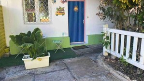 Una casa amb una porta blava, una finestra amb reixatge metàl·lic i una tanca blanca.