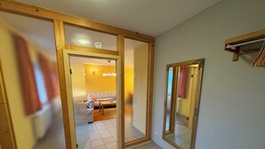 Un pasillo con suelo de madera, un espejo y una puerta que da a una sala de estar con un sofá y una mesa.