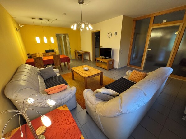 Ein Wohnzimmer mit zwei Sofas, einem Couchtisch und einem Essbereich mit Tisch und Stühlen.
