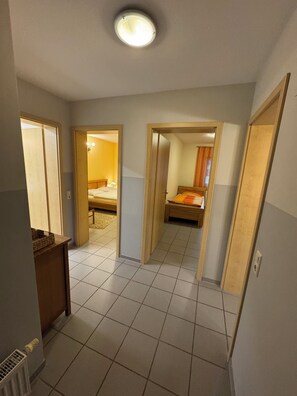 Ein Hotelzimmer mit Fliesenboden, einem Bett, einem Schreibtisch und einem Kleiderschrank.