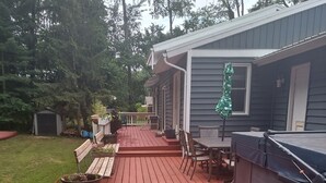 Ein Holzdeck mit Barbereich, Gartenmöbeln und einem Gartenhaus im Hinterhof.
