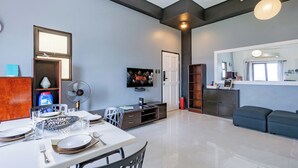 A modern living room with a dining area, a television, and a large window.