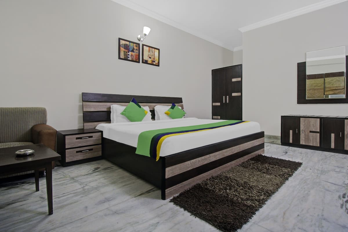 Un dormitorio con cama, mesita de noche, cómoda, sofá y espejo.