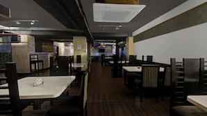 Interior de restaurante con varias mesas y sillas, una barra y una pared con diseño.