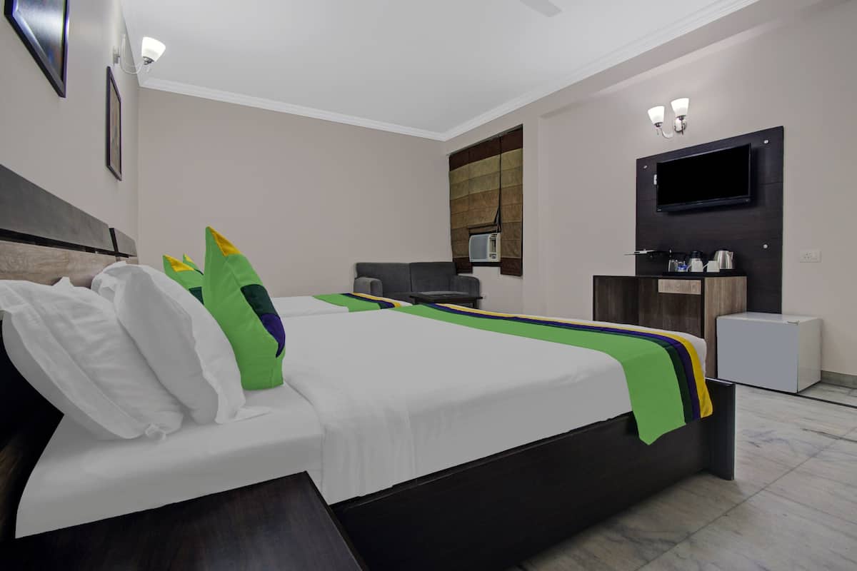 Una habitación de hotel moderna con una cama grande, un televisor de pantalla plana, un pequeño espacio para sentarse y un mini bar.
