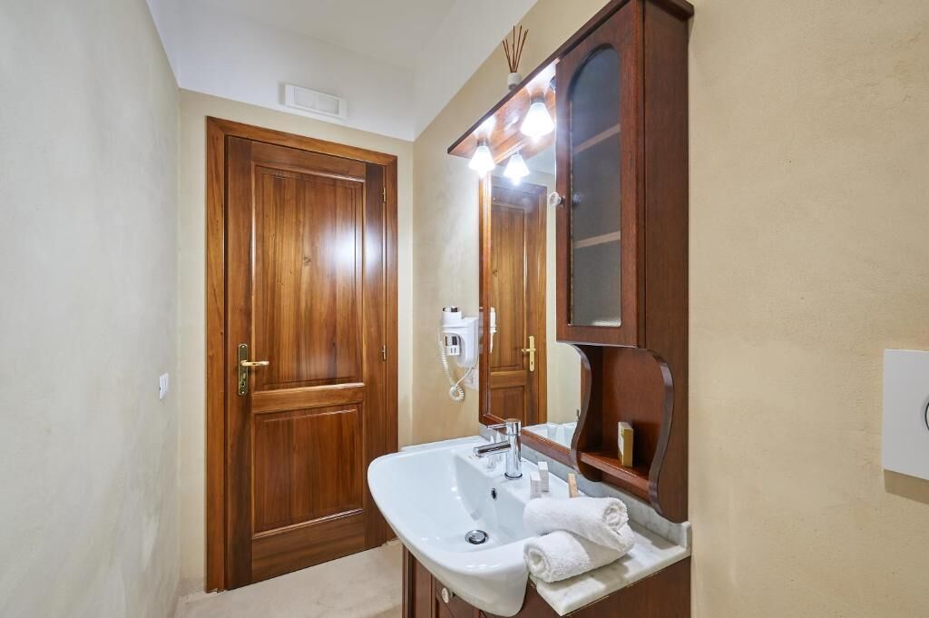 A bathroom with a wooden door, a white sink, a mirror, and a towel rack.