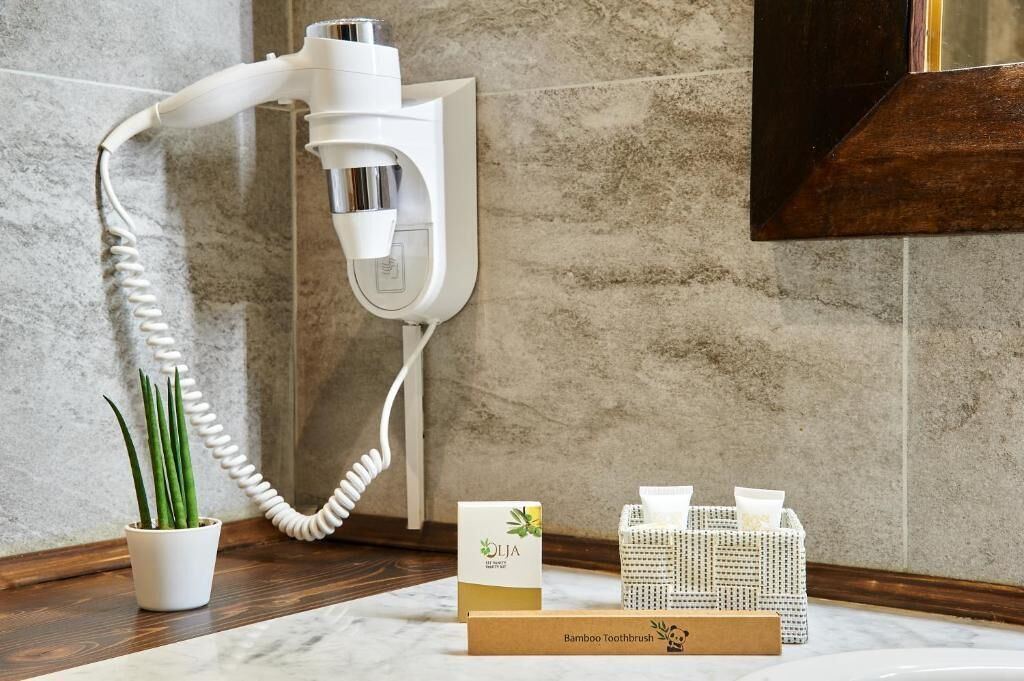 Un secador de pelo montado en la pared, un porta cepillos de dientes de bambú y una caja con la etiqueta "Olja Bamboo Toothbrush".