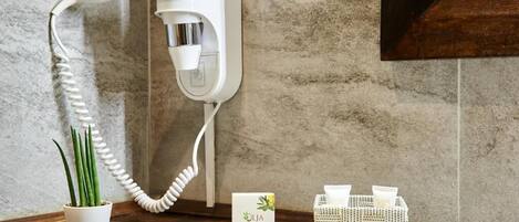 Un secador de pelo montado en la pared, un porta cepillos de dientes de bambú y una caja con la etiqueta "Olja Bamboo Toothbrush".