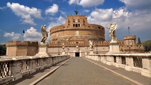 Un edifici gran i històric amb una cúpula central i estàtues als costats d'un pont que hi condueix.
