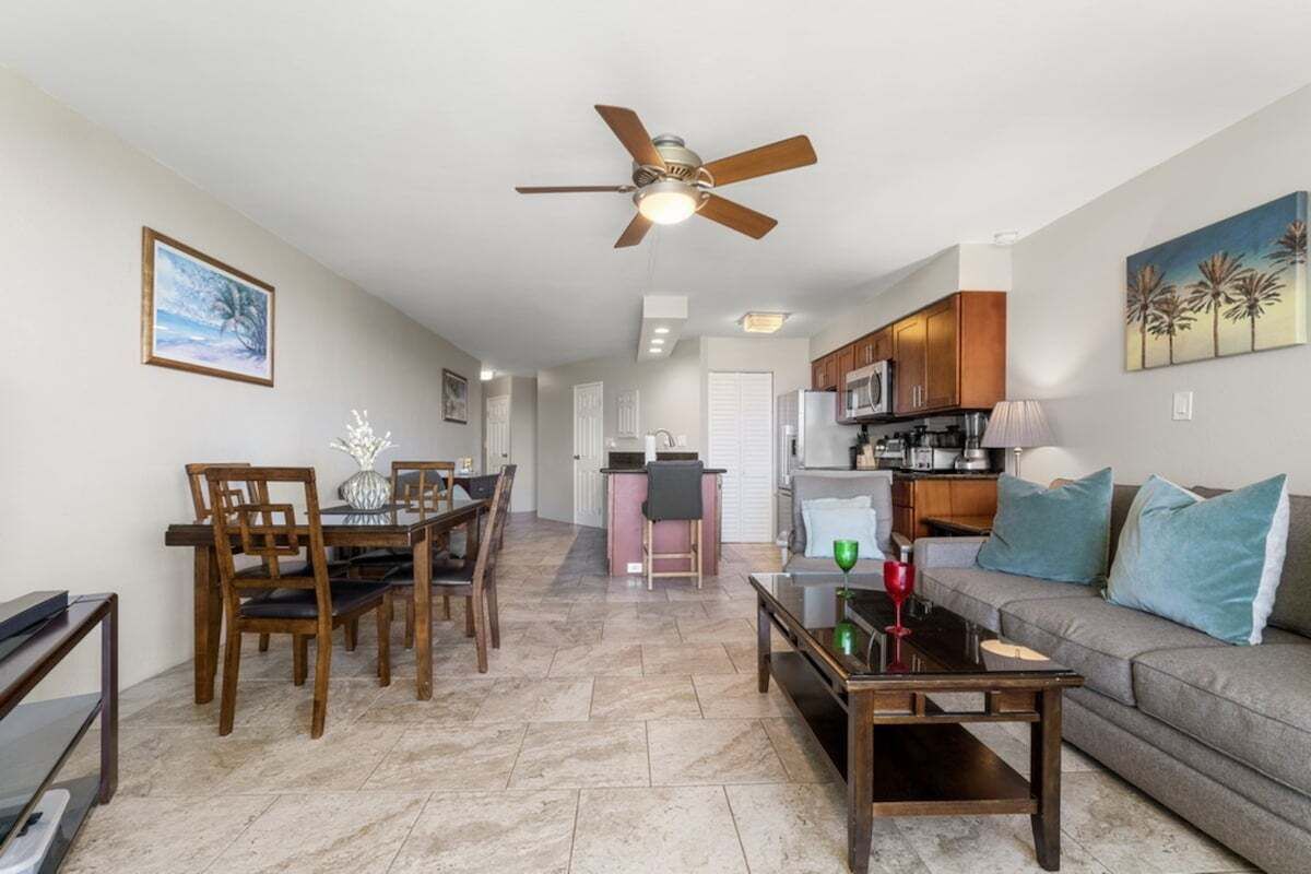 Una sala de estar con comedor, una cocina y un ventilador de techo.