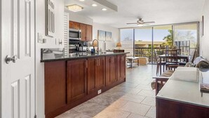 A modern kitchen with wooden cabinets, a large island, and a dining area with a view.